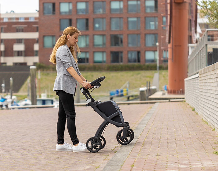 Woman going up a sidewalk with rollator