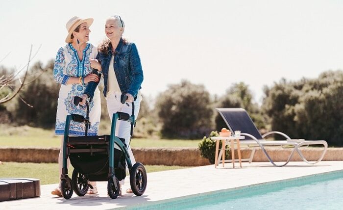 Frau geht mit einem Rollz Motion Performance Rollator in der Nähe eines Schwimmbads