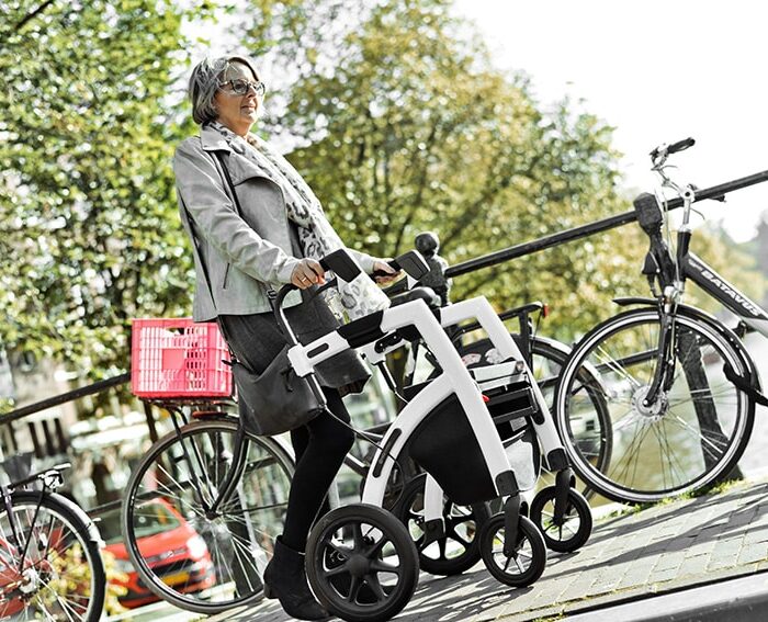 Frau die mit einem Rollator auf einer Piste geht