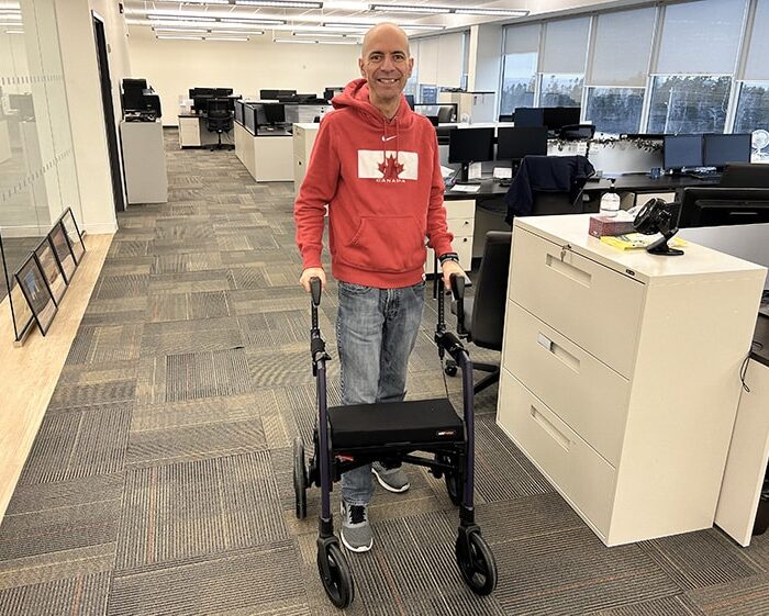 Mann, der einen Rollz Motion Rollator benutzt, um seine Behinderung bei der Arbeit auszugleichen